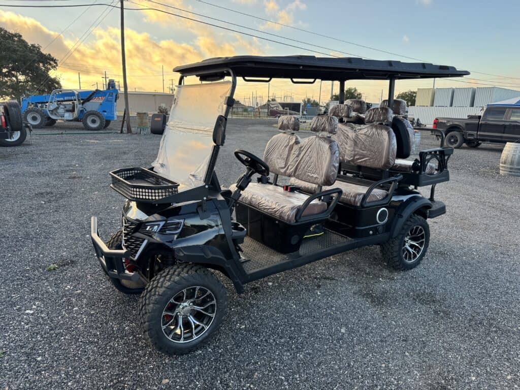 Black electric golf cart with four seats and canopy at auction lot.