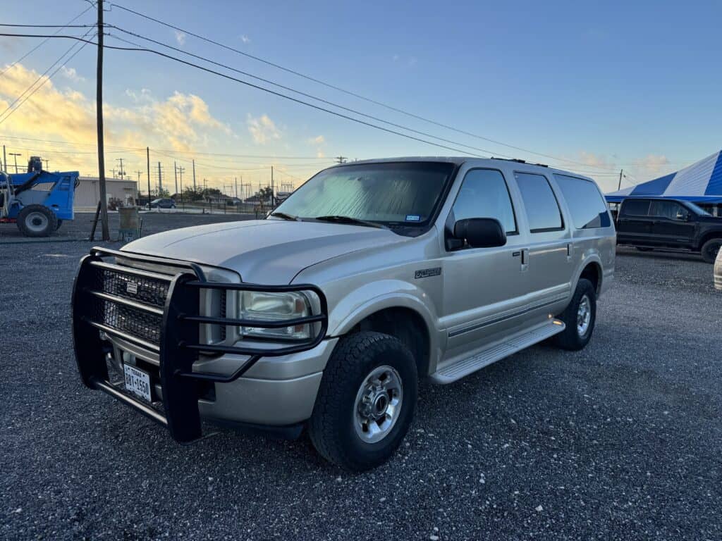 Silver Ford Excursion SUV with front grille guard at auction lot.