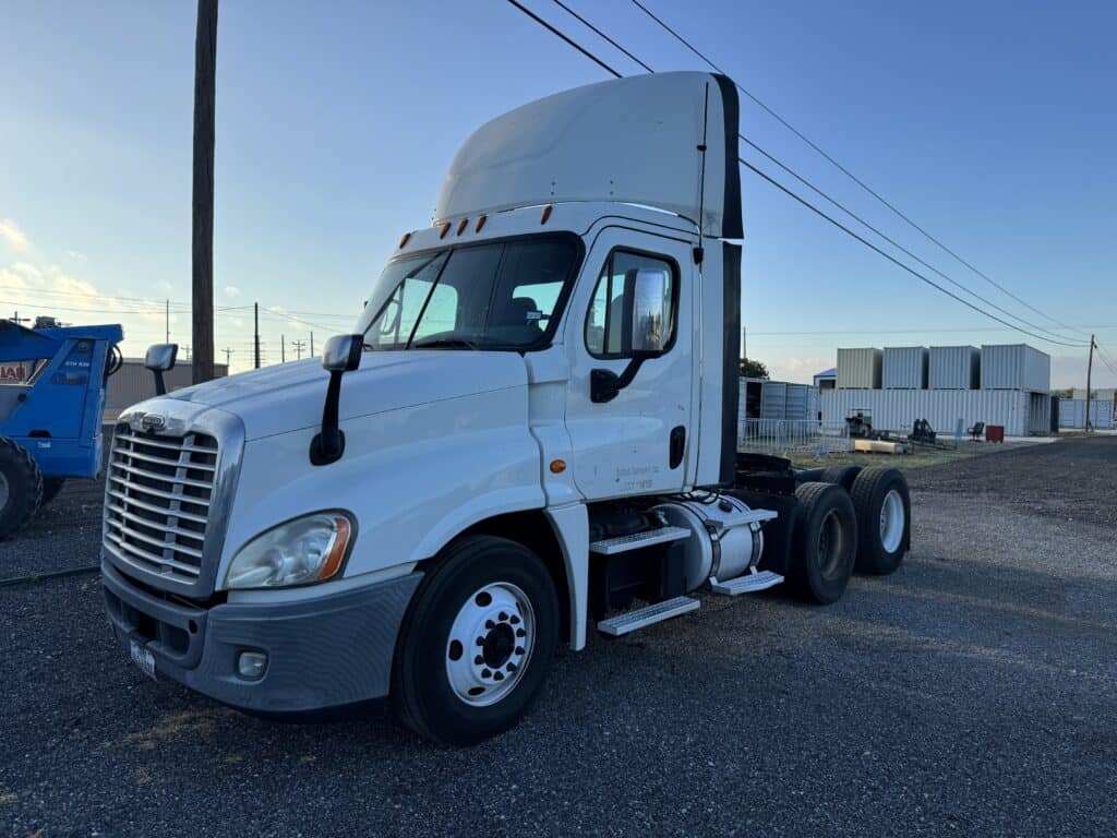 White semi truck at auction site with clear sky background.
