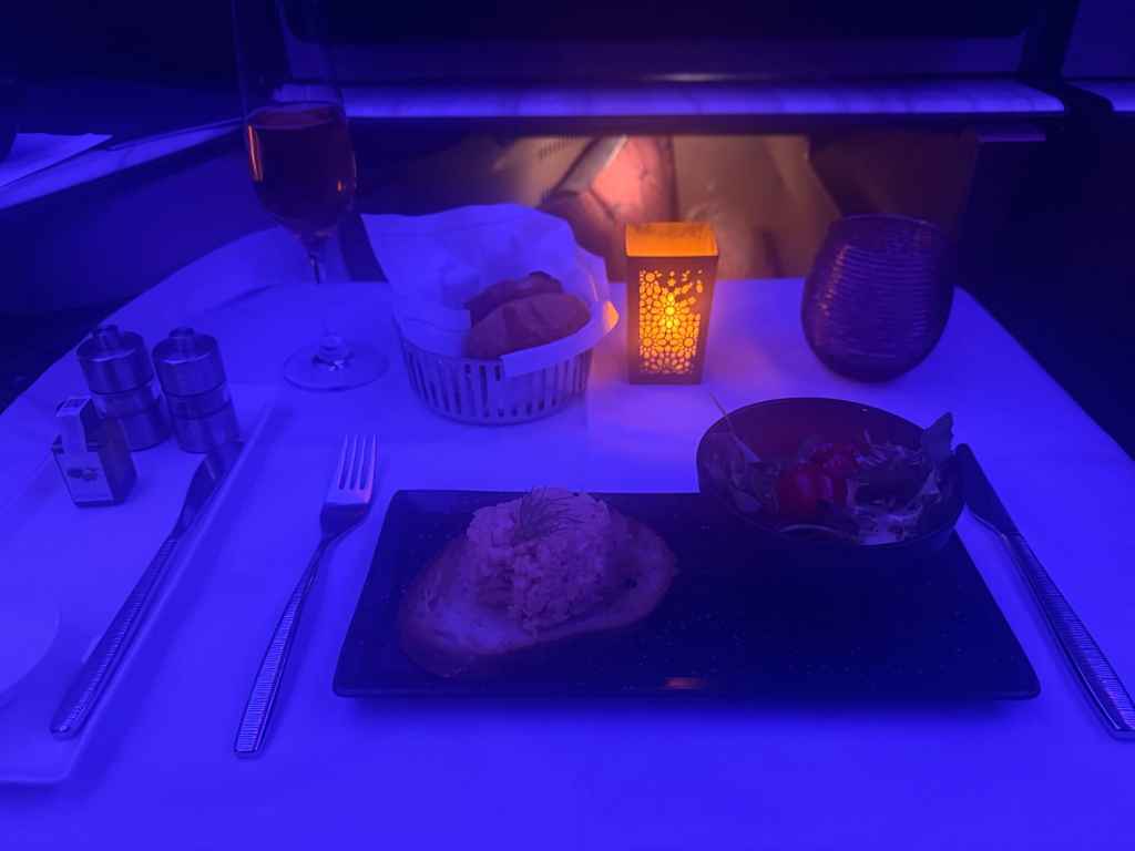 A romantic dinner setting with a plate of bread, salad, wine, and candlelight ambiance.