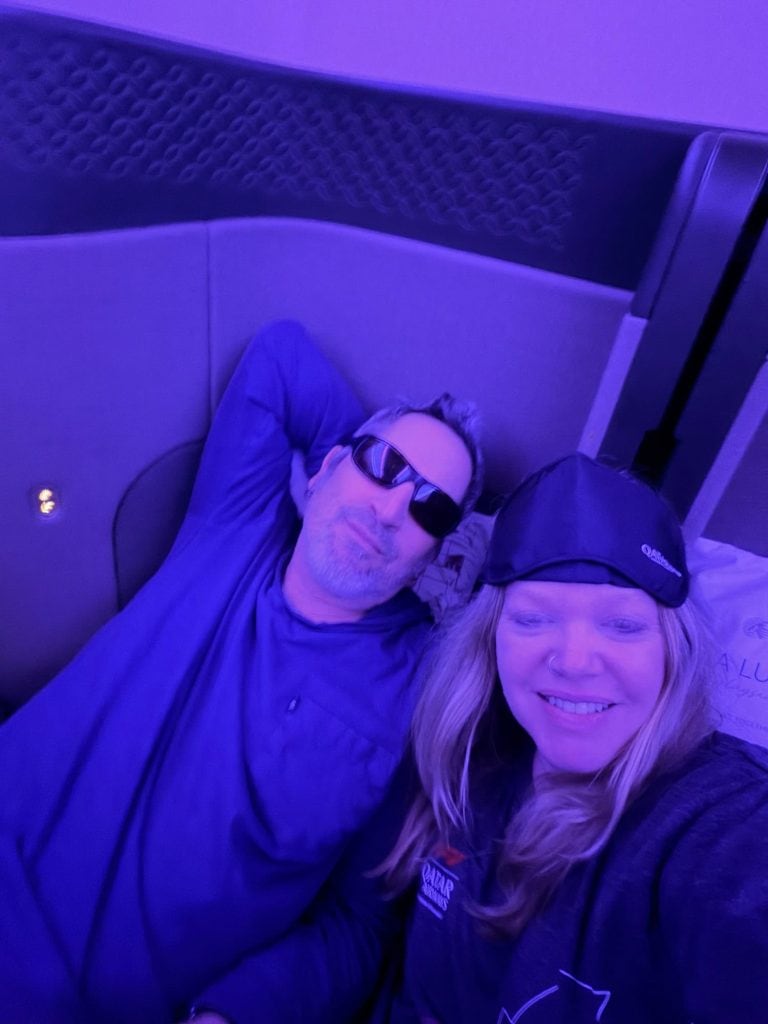 LiAnn and Theo relaxing together in a cozy, purple-lit setting during their travel adventure.