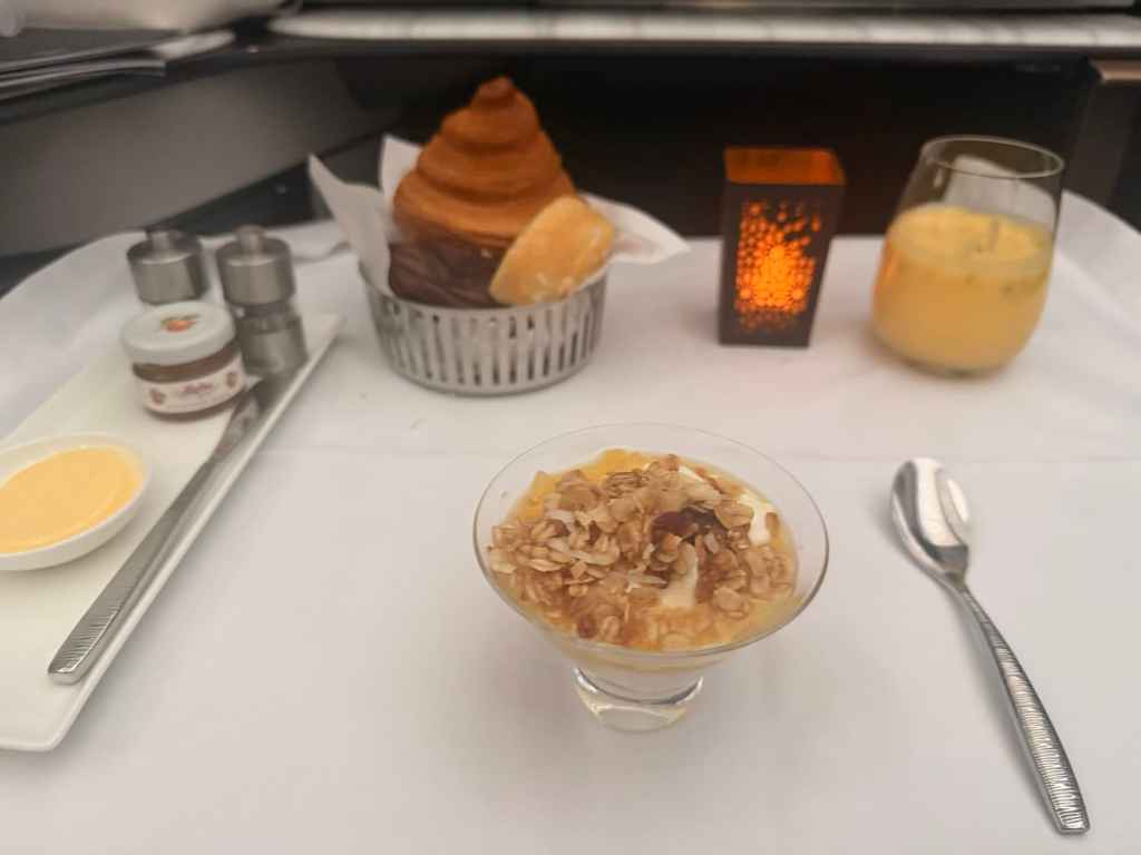 Delicious dessert and coffee served during flight, featuring a pastry, parfait, and a warm drink for.