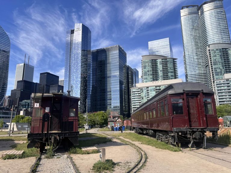 Historic trains against modern cityscape backdrop.