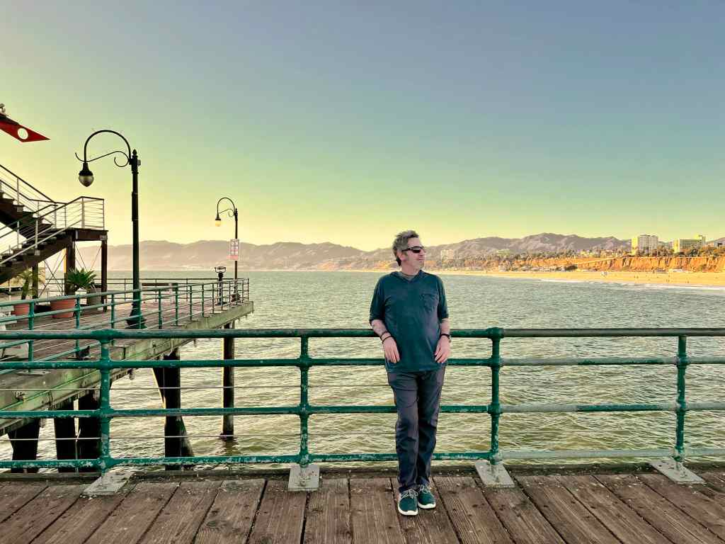 Seaside pier with a person enjoying the sunset by the water.