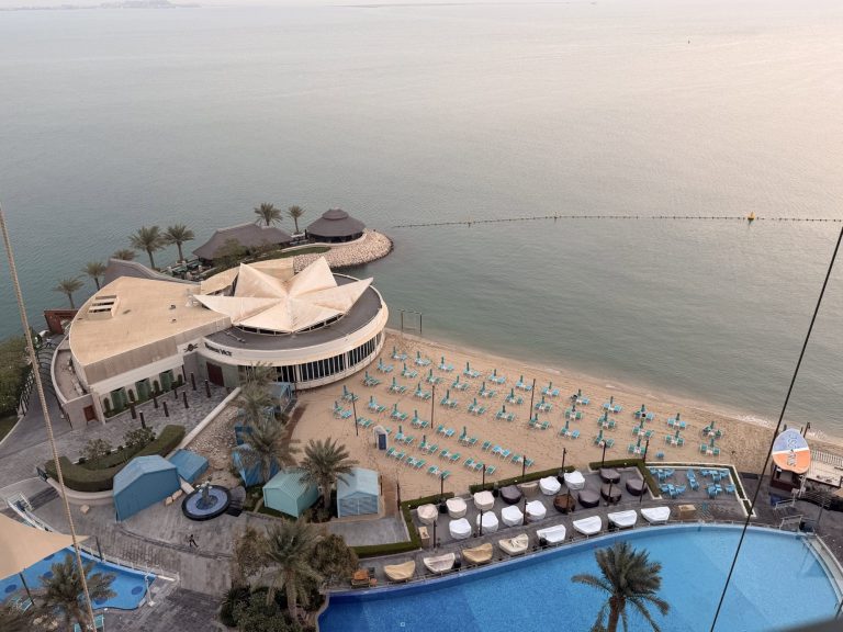 Relaxing seaside resort with pool, sunbeds, and ocean views at sunset.