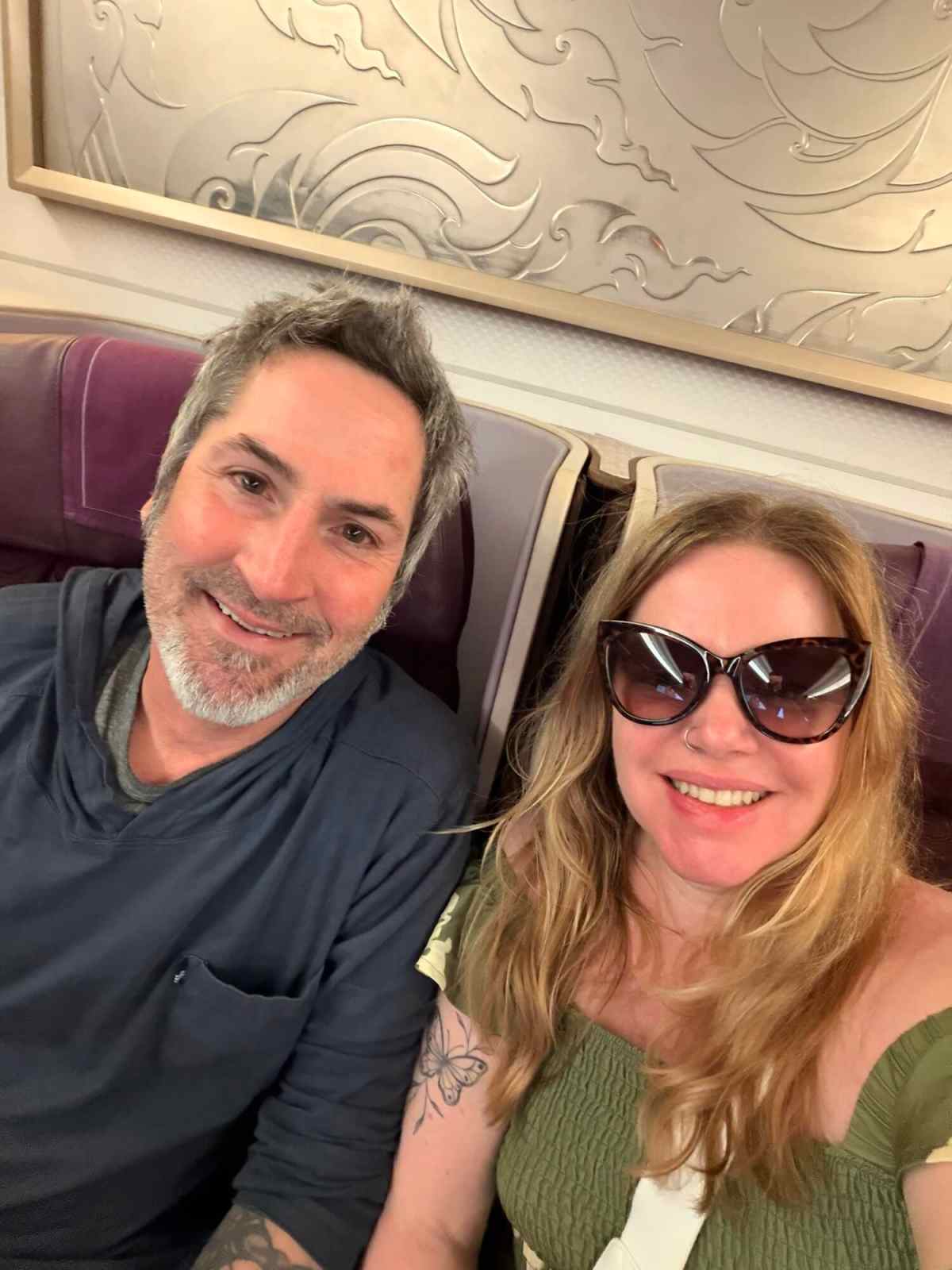 Happy couple smiling on an airplane, traveling adventure with scenic background.