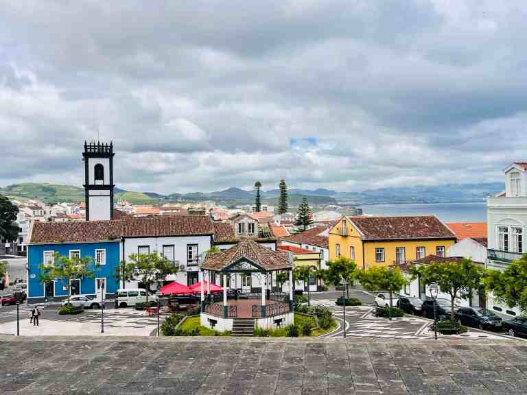 Vibrant seaside town featuring colorful houses, a clock tower, and a view of the ocean in the backgr.