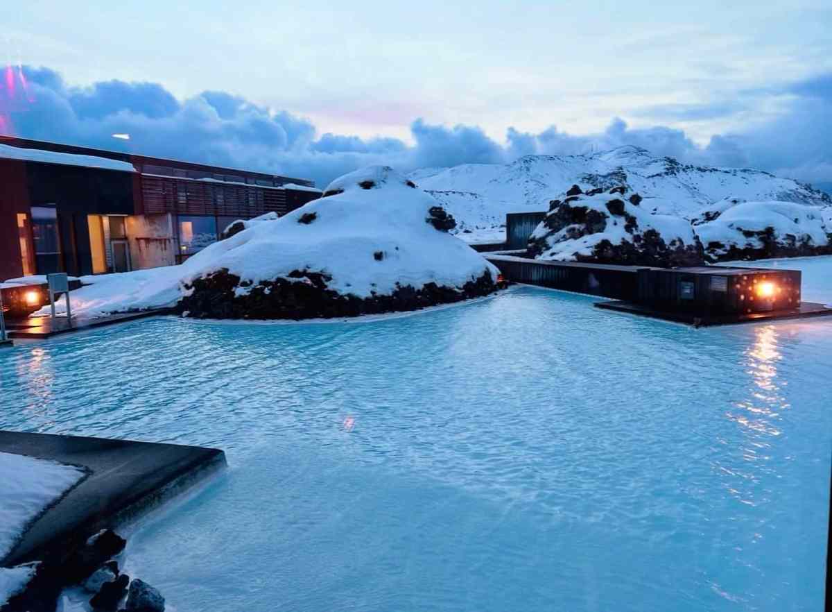 Hot spring pool with snow-covered rocks and mountain views in Iceland.