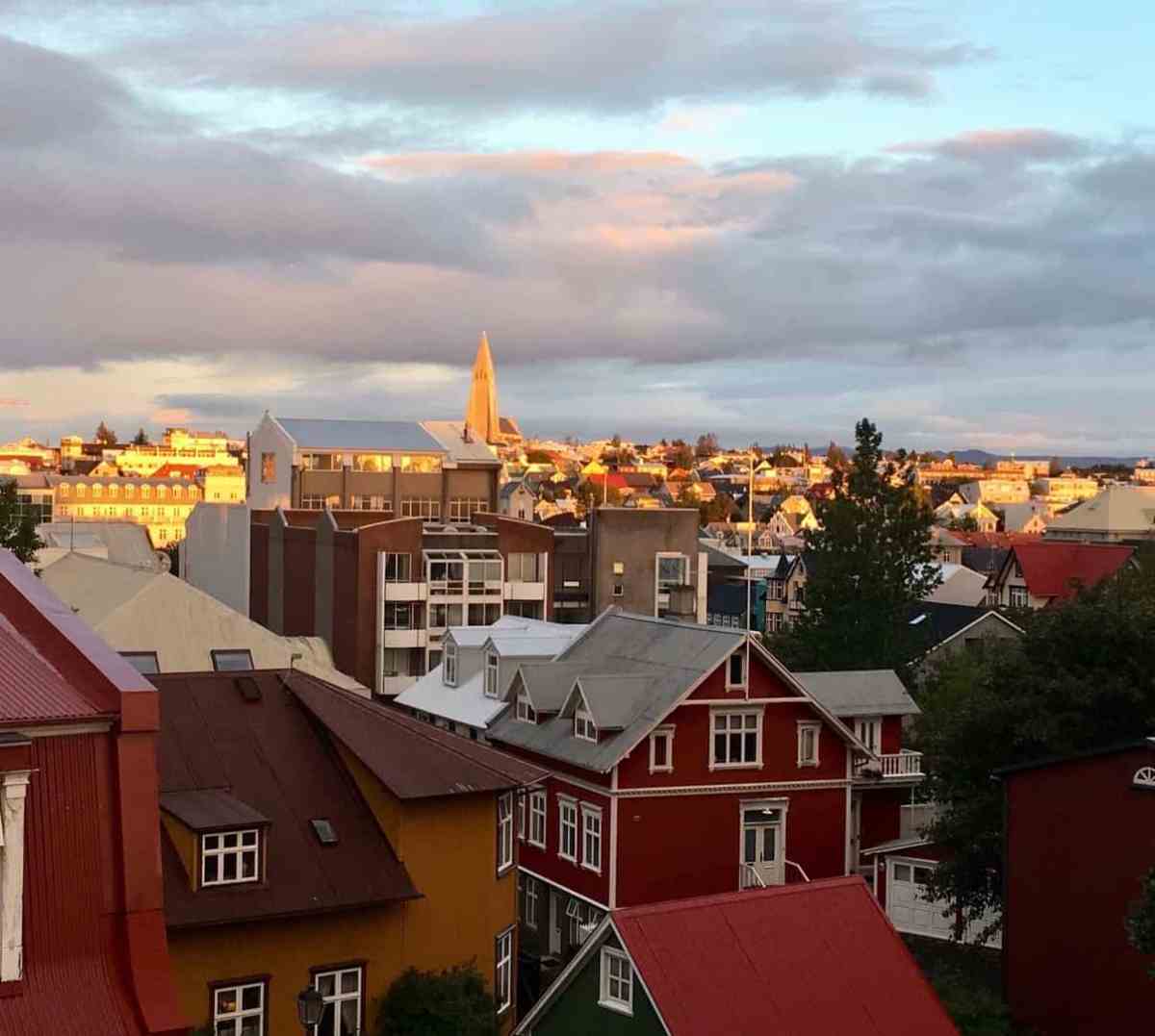 Scenic cityscape with colorful houses and church steeple at sunset.