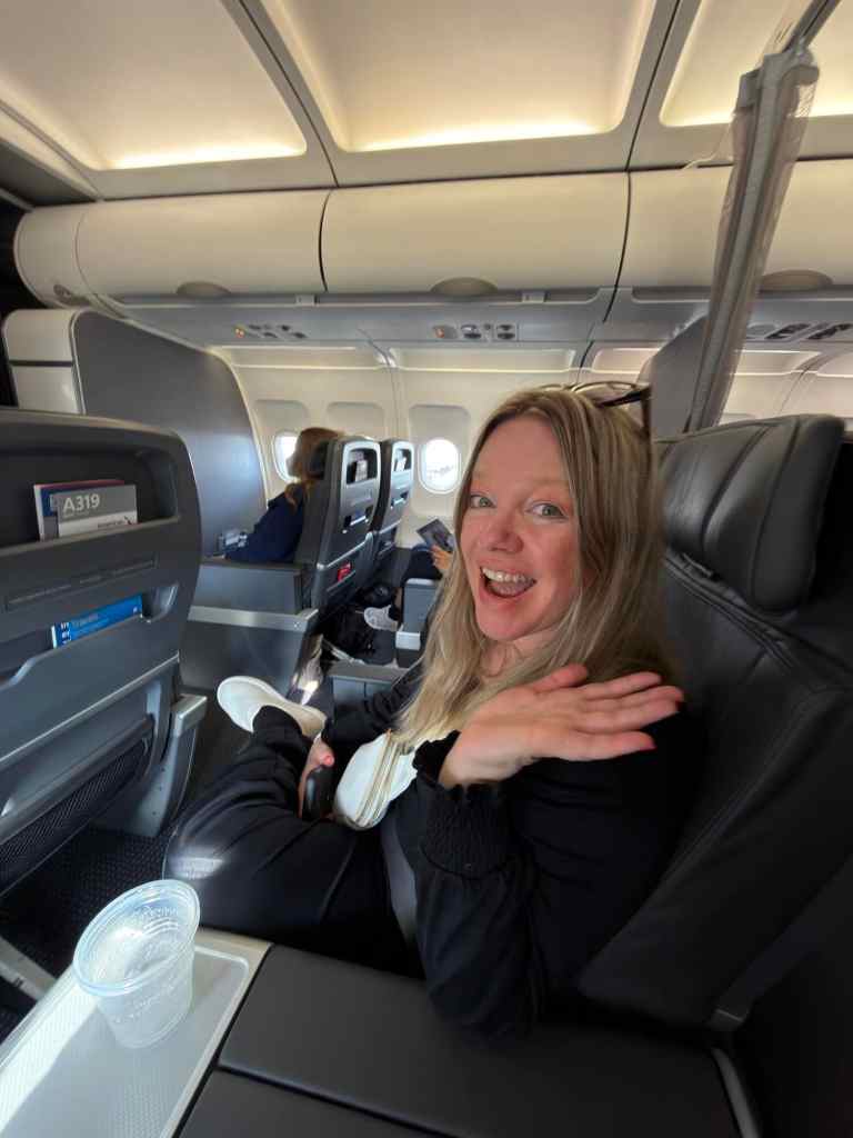 Cheerful woman smiling on airplane, enjoying travel experience.