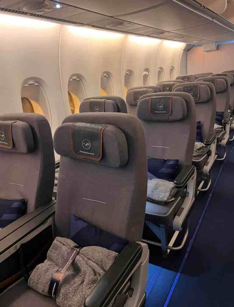 Airplane interior with rows of gray seats and overhead compartments.