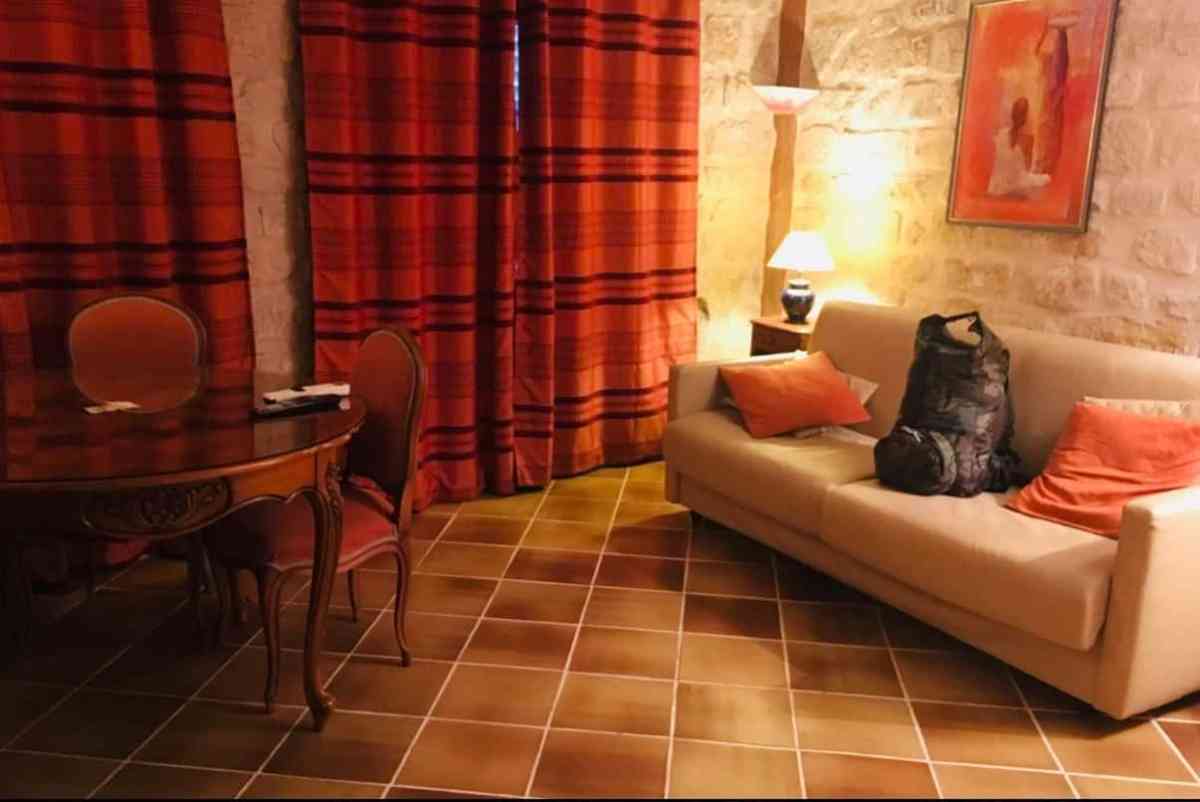 Warmly lit living room with sofa, curtains, and dining area, perfect for relaxing or socializing.