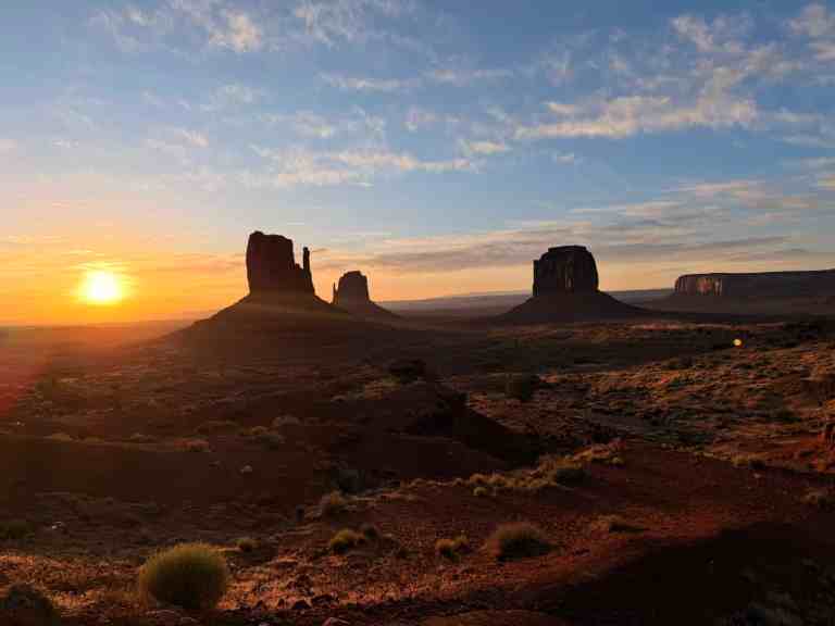Sunset over Monument Valley with iconic sandstone formations and vibrant sky.