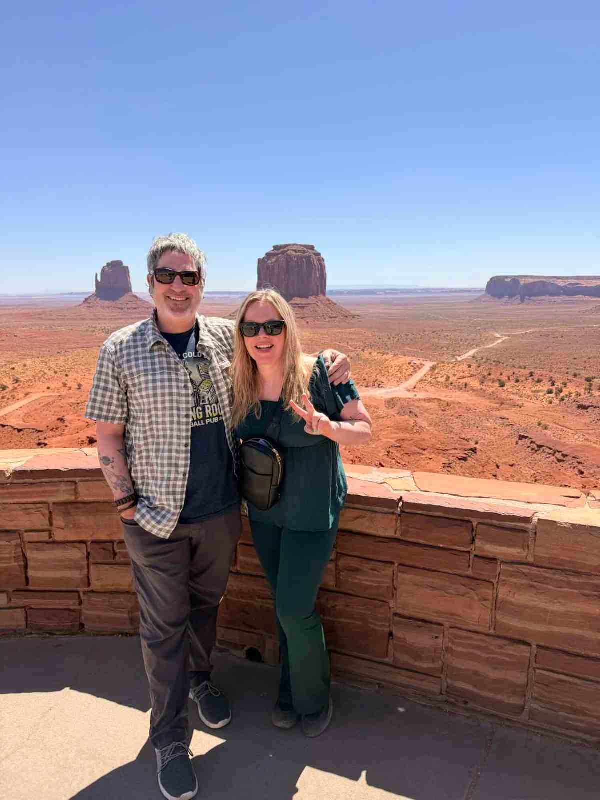 Happy couple visiting Monument Valley with iconic rock formations in the background.