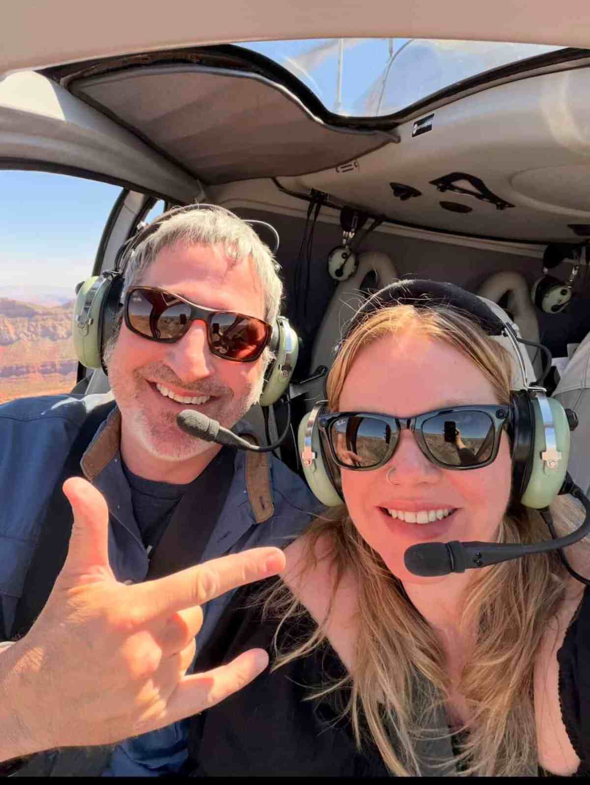 Happy couple taking a helicopter tour over the Grand Canyon with headsets on.