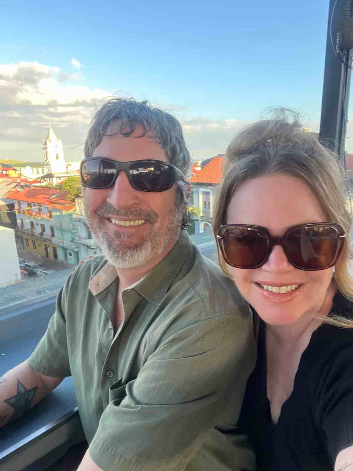 LiAnn and Theo wearing sunglasses enjoying city view during travel.