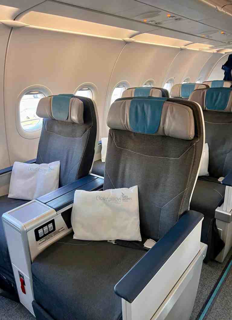 Airplane interior with empty seats and blue headrests.