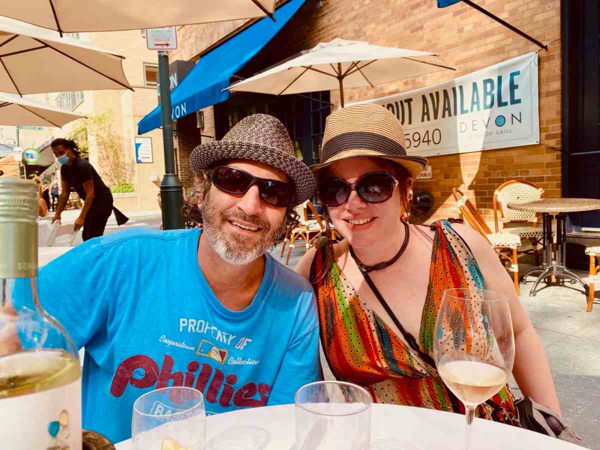 LiAnn and Theo enjoying outdoor dining with wine in a city street.
