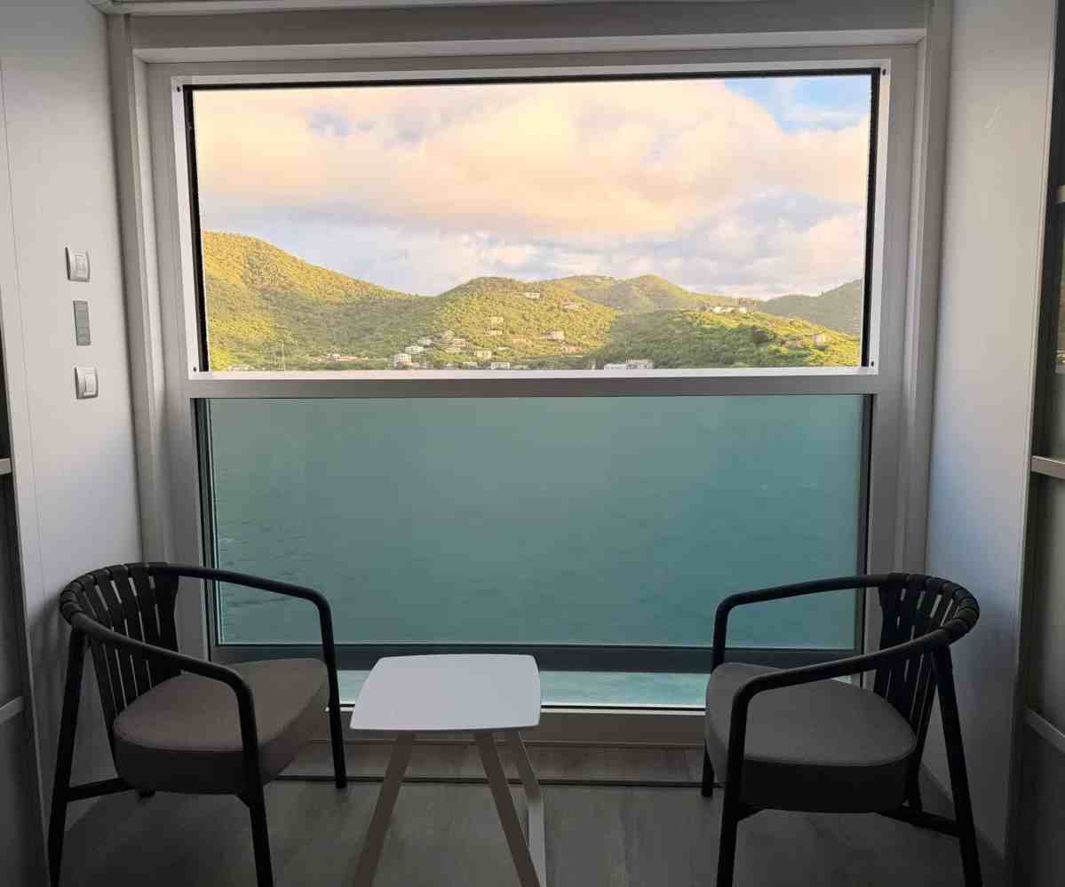 Hotel room with a view of mountains and water through large window.