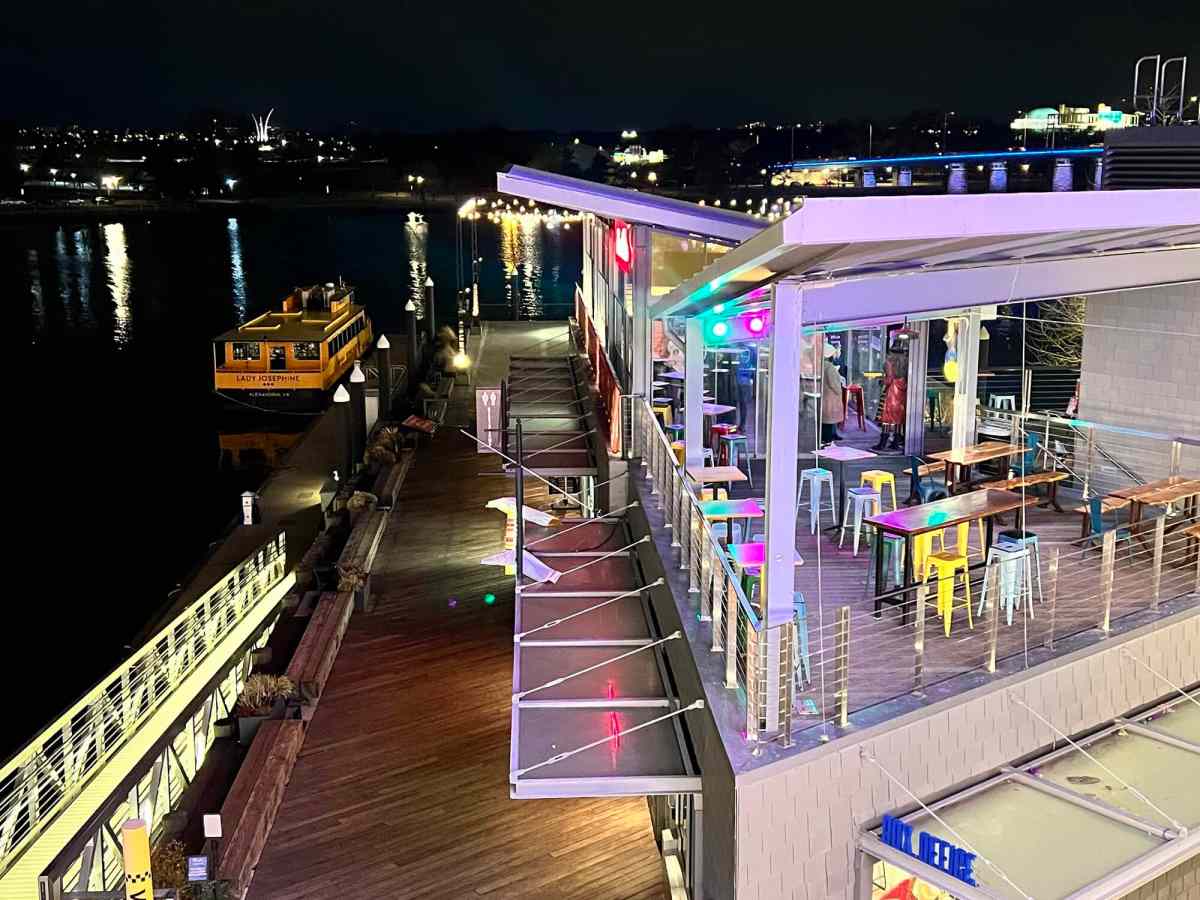 Night view of a floating restaurant with colorful lights on a river.