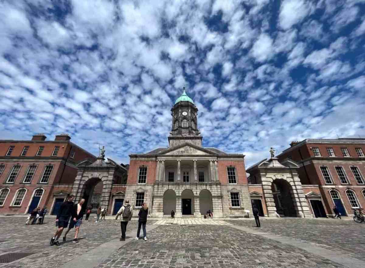 Dublin City Hall with people walking in front and a dramatic sky.