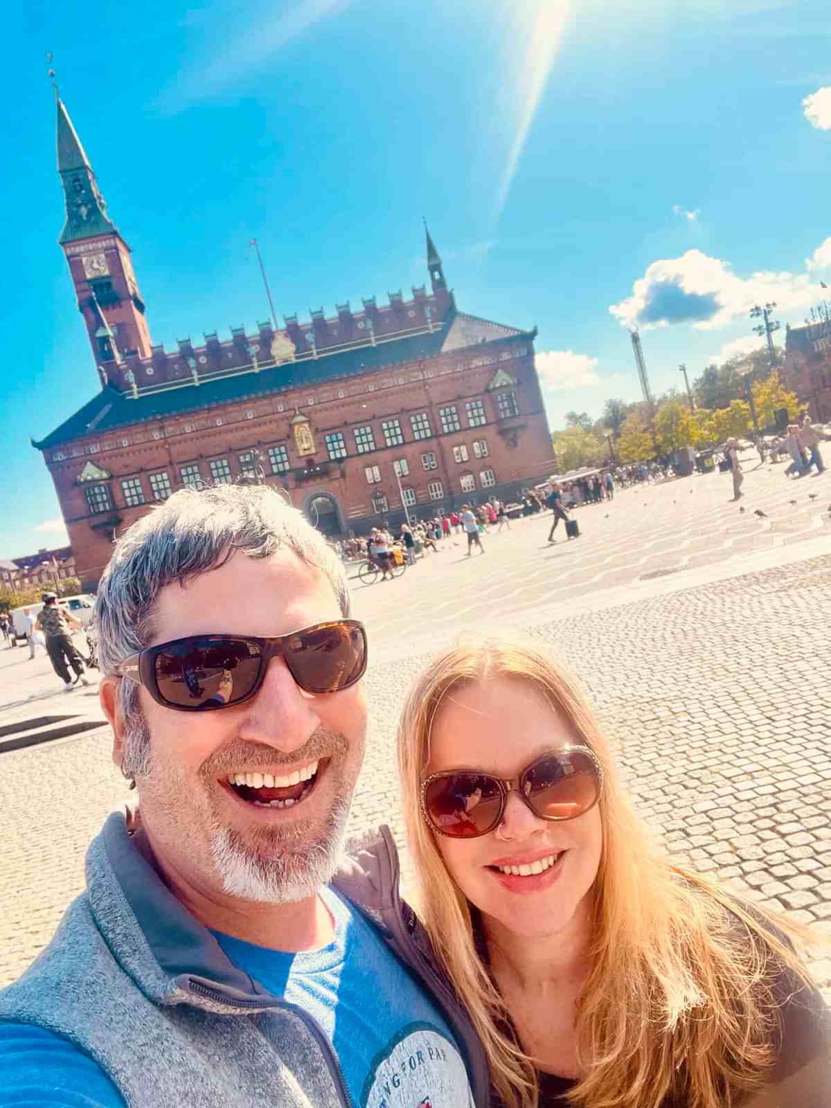 Happy couple sightseeing in Riga with historic building in background.