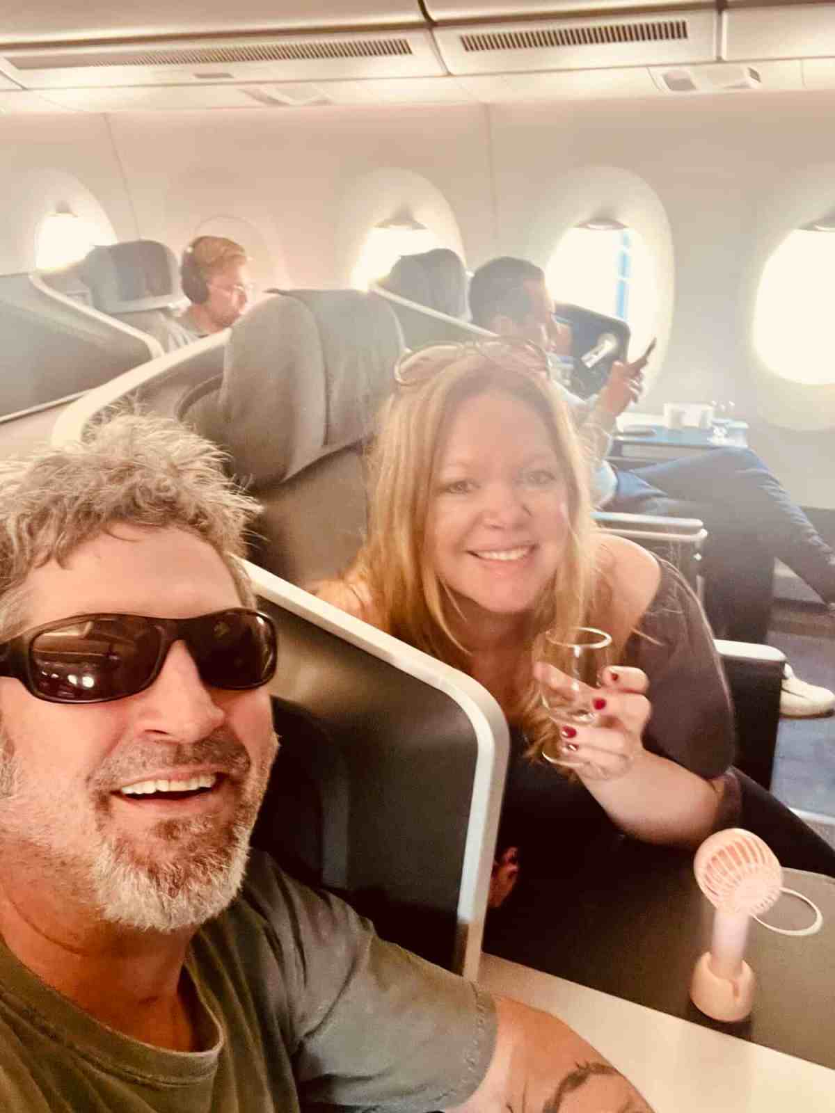 Happy couple traveling on airplane with friends, enjoying flight experience.