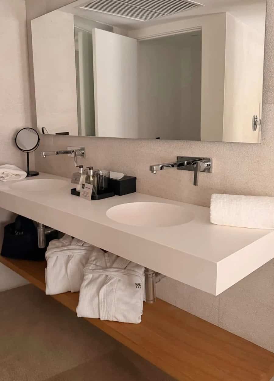 Contemporary hotel bathroom with double sink, mirror, and neatly arranged toiletries.