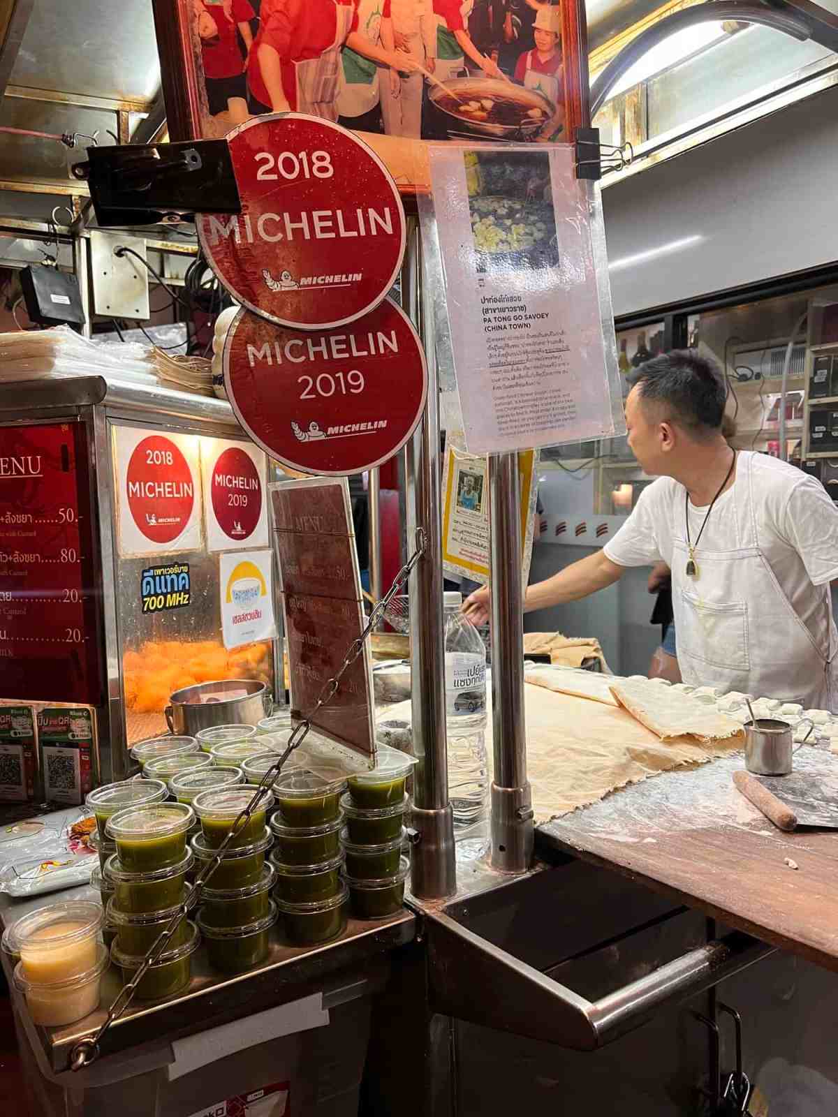 Food stall with Michelin awards 2018 and 2019 in a busy market.