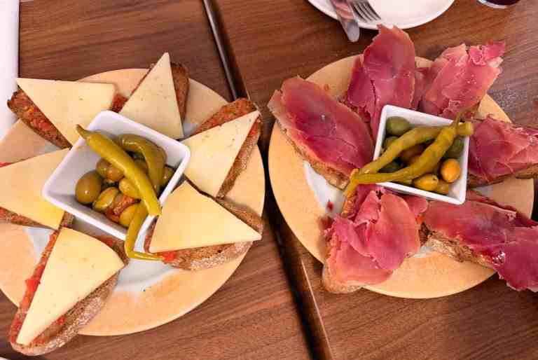 Delicious cheese, cured meats, and pickles on a travel-themed platter.