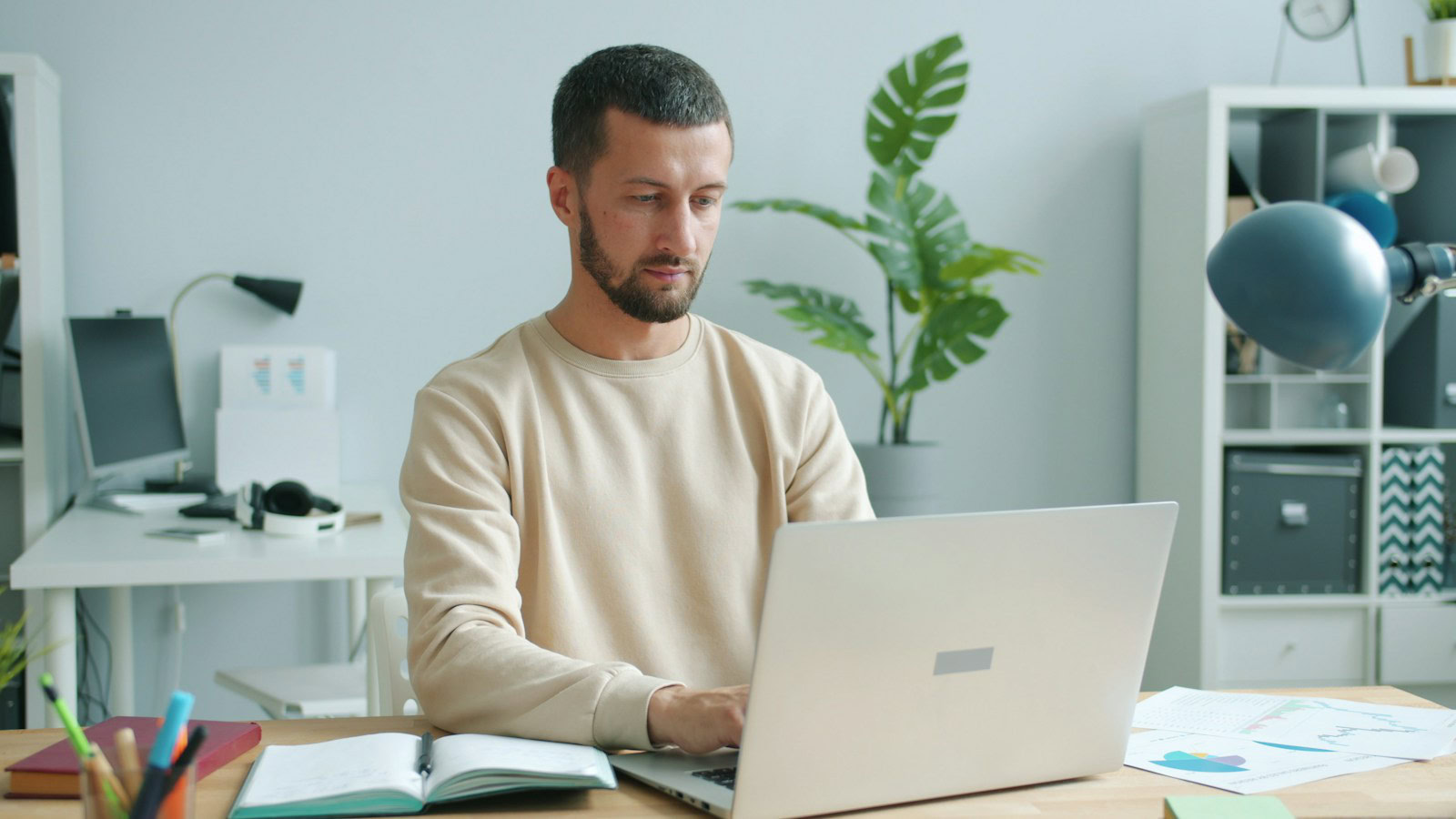 A man typing on his laptop in a bright office