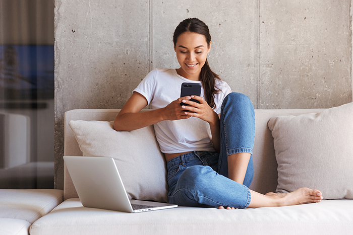 A busy professional multitasking between a laptop and a smartphone, staying connected and productive in the digital age.