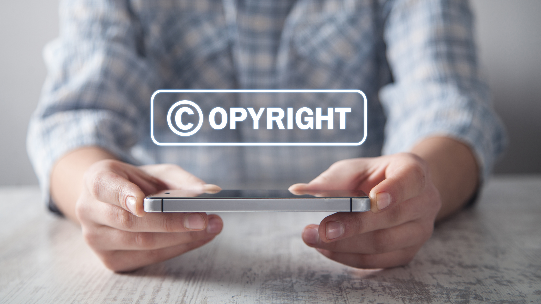 A person holding a mobile phone exploring intellectual property, understanding copyright laws and digital rights.