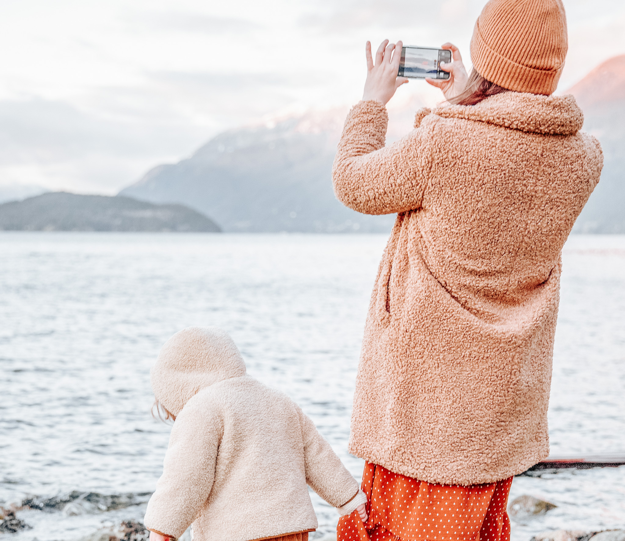 A mother and child enjoying quality time at the beach, capturing memories through photography.