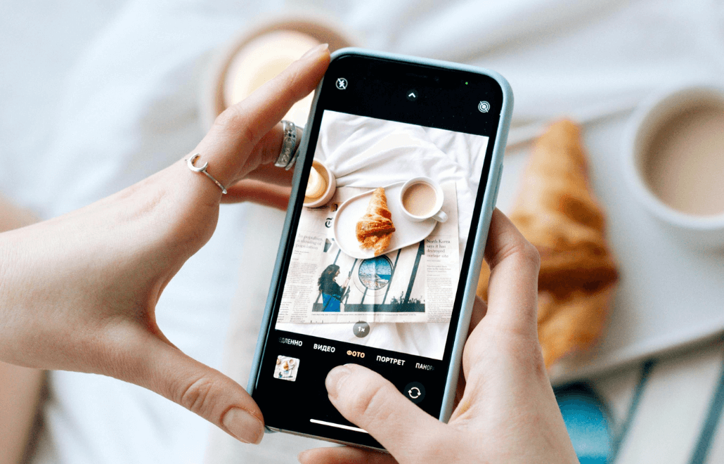 A woman capturing a photo of a freshly baked bread to share as user-generated content on social media.