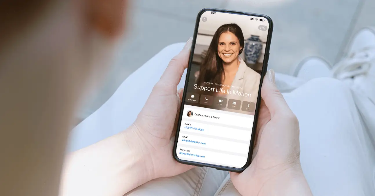 A person holding a smartphone showing a digital contact card for Life In Motion Marketing, featuring a friendly professional, symbolizing direct client communication and brand engagement for a digital marketing agency.