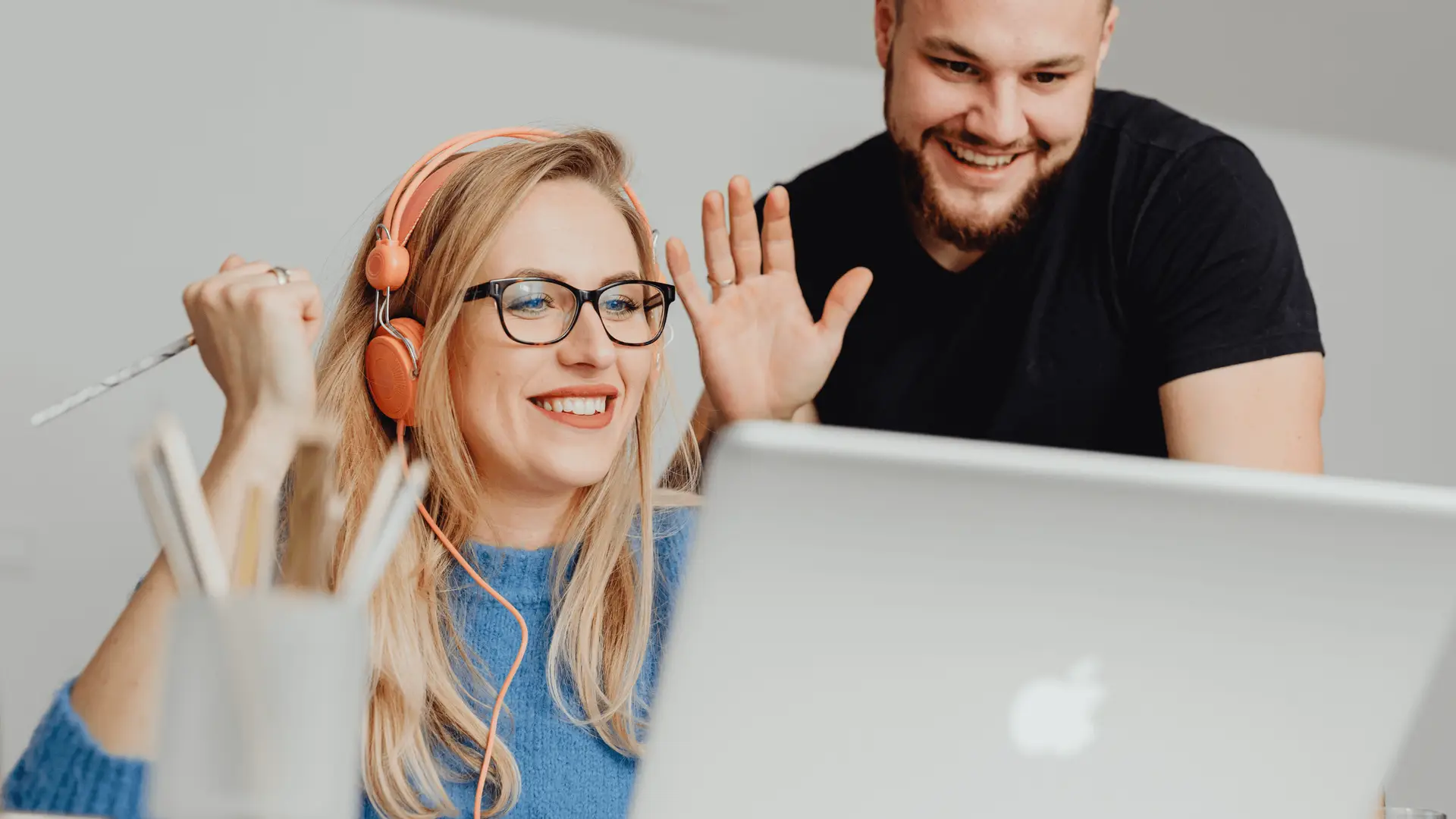 A smiling sales team collaborating over a laptop, demonstrating how RevStream CRM automation replaces manual spreadsheets to improve marketing ROI and team efficiency.