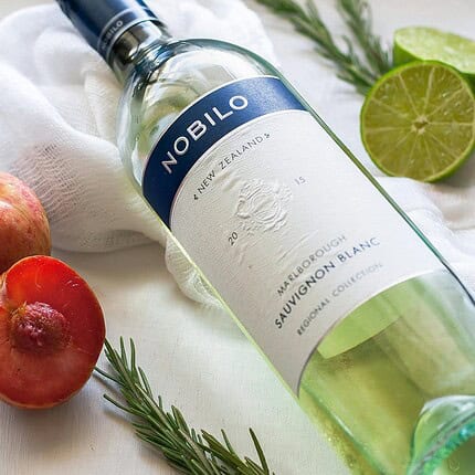 Fiole de gin Nobilo avec citron vert, pommes et herbes aromatiques.