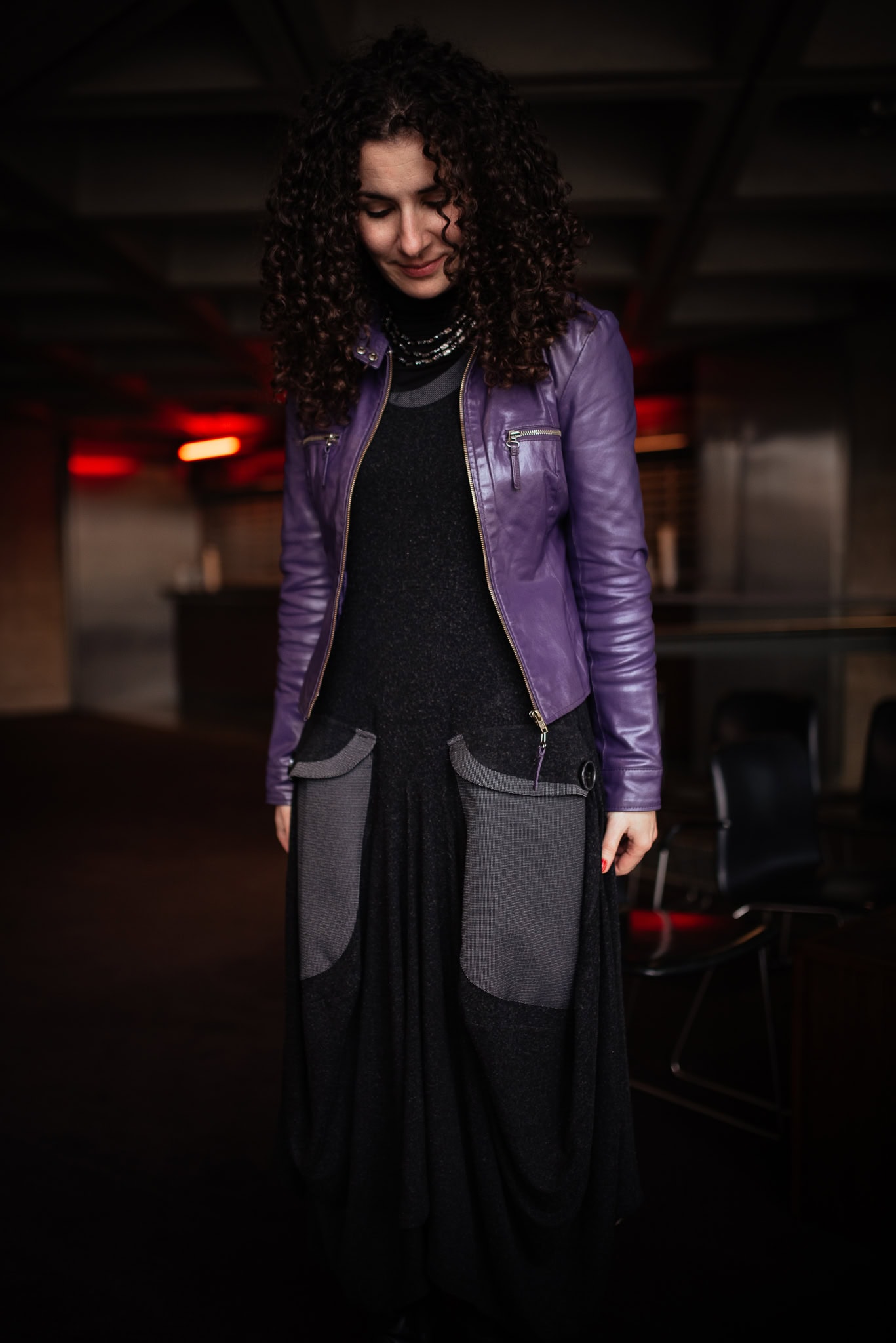 Valerie Teller, a woman with curly hair, wears a purple jacket and black dress, photographed by a London brand photographer.