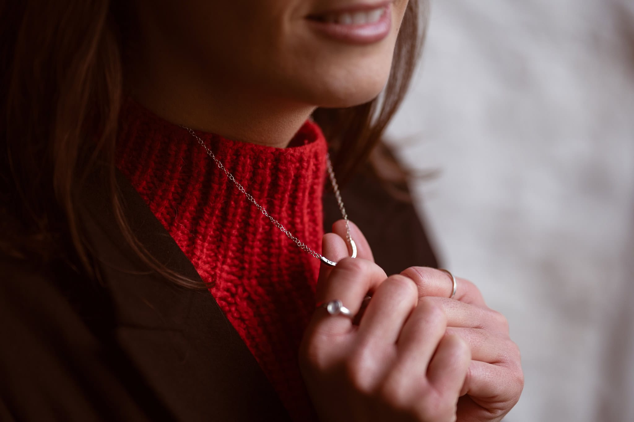 Jess Ratcliffe, a coach, wears a red jumper and a silver necklace, captured by a London brand photographer.