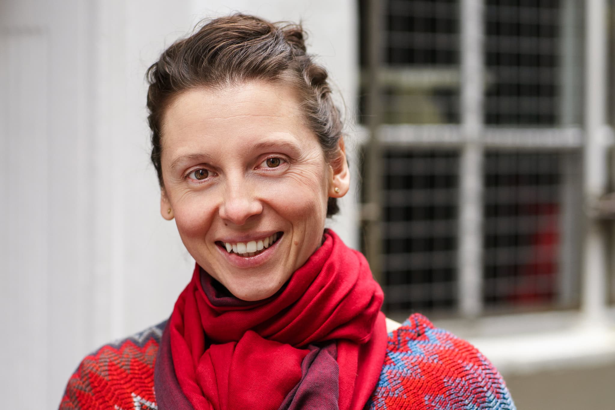 Moni Soos smiles warmly, her authentic presence captured in soft light by a London brand photographer.