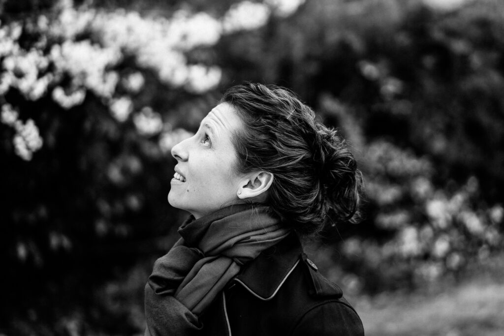Moni Soos, a woman with her hair in a bun, looking up with a gentle smile, captured by a London brand photographer.