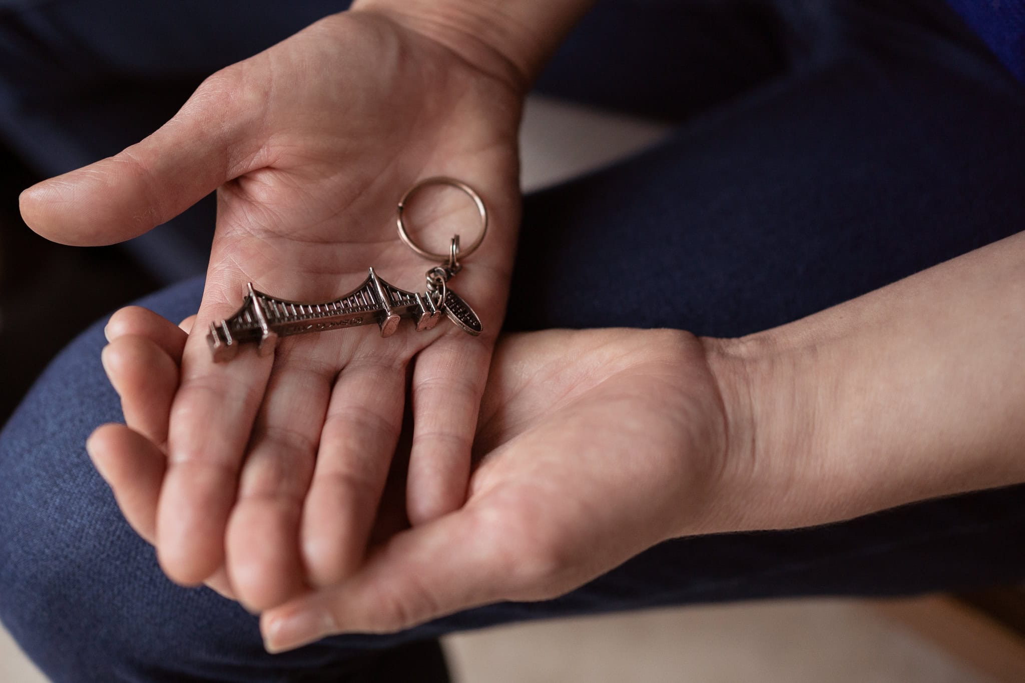 Claire Mackinnon's hands hold a miniature bridge keychain, a memento from a London trip.