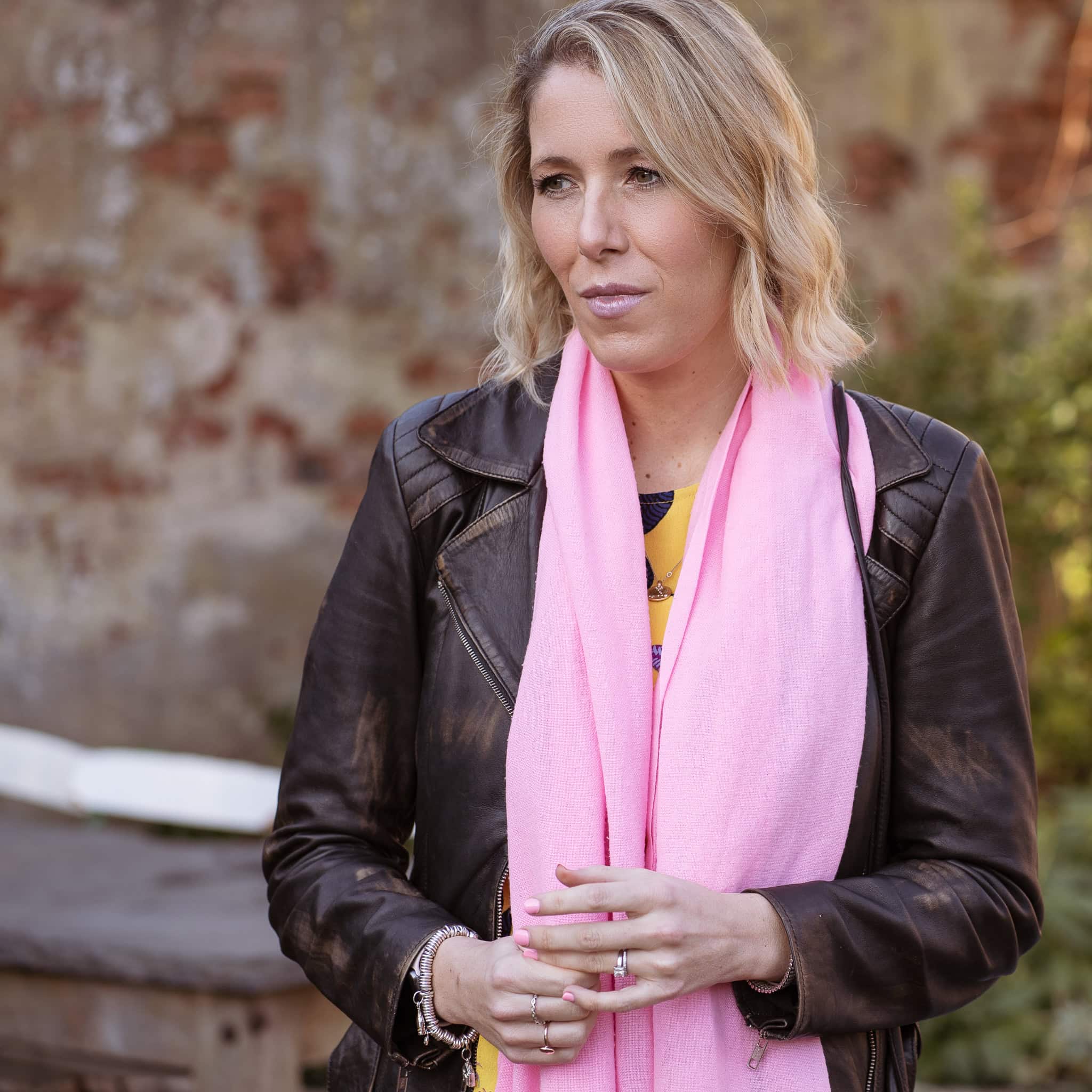 Jo Garside, a confident woman in a leather jacket and pink scarf, photographed by a London brand photographer.