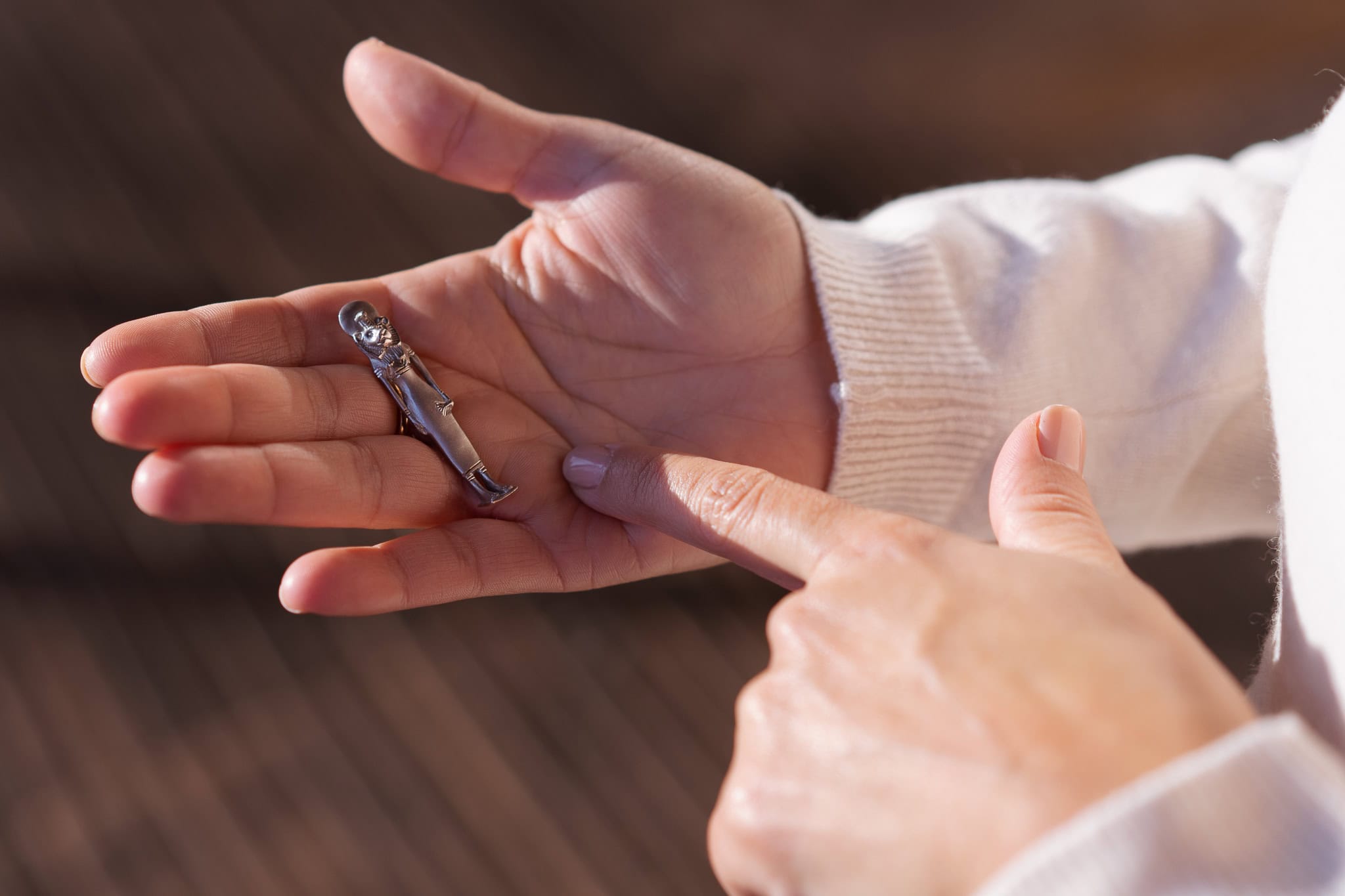 Eleonora Chessa holds a small silver figurine in her palm, with a finger pointing towards it.