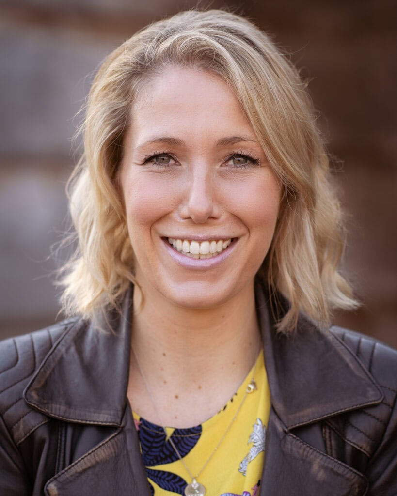 Jo Garside, a confident coach, smiles warmly in a natural light portrait by a London brand photographer.