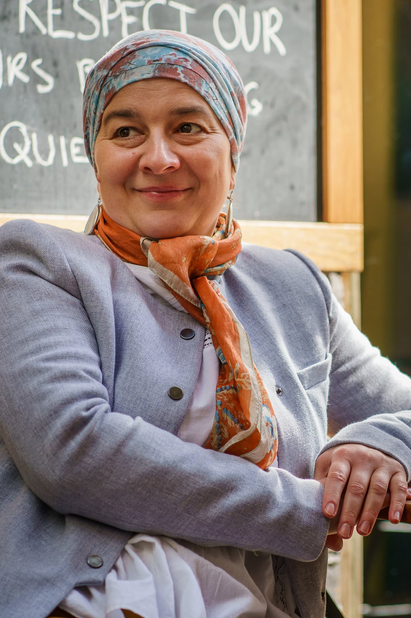 A warm, authentic portrait of a woman with a colourful headscarf and orange scarf, captured by a London brand photographer.