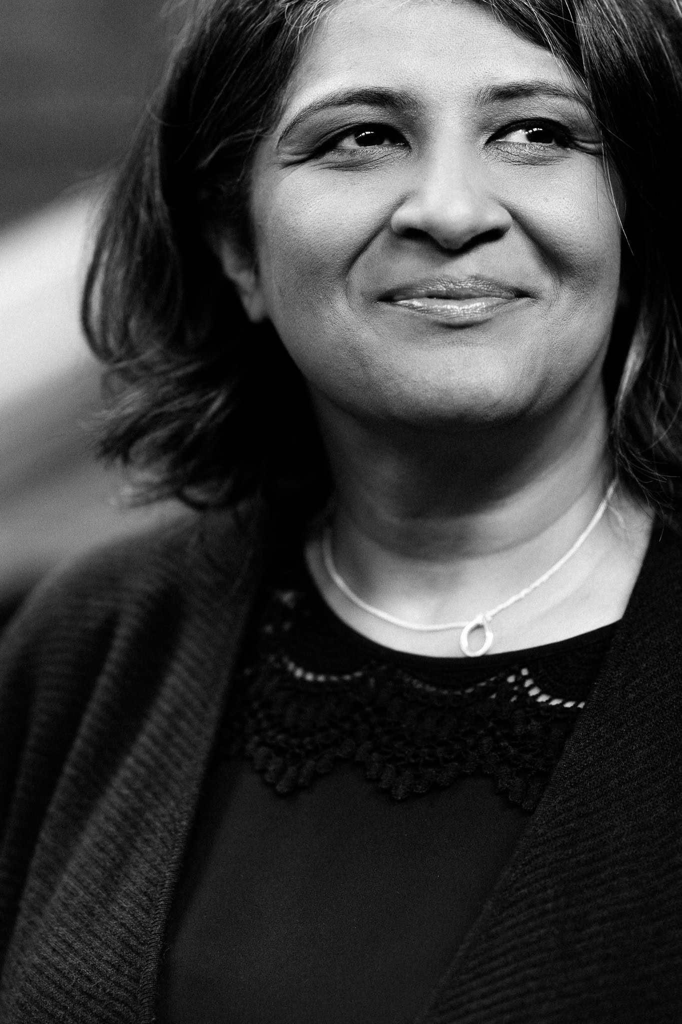 Black and white portrait of Anita Patel, a confident woman with a warm smile, captured by a London brand photographer.