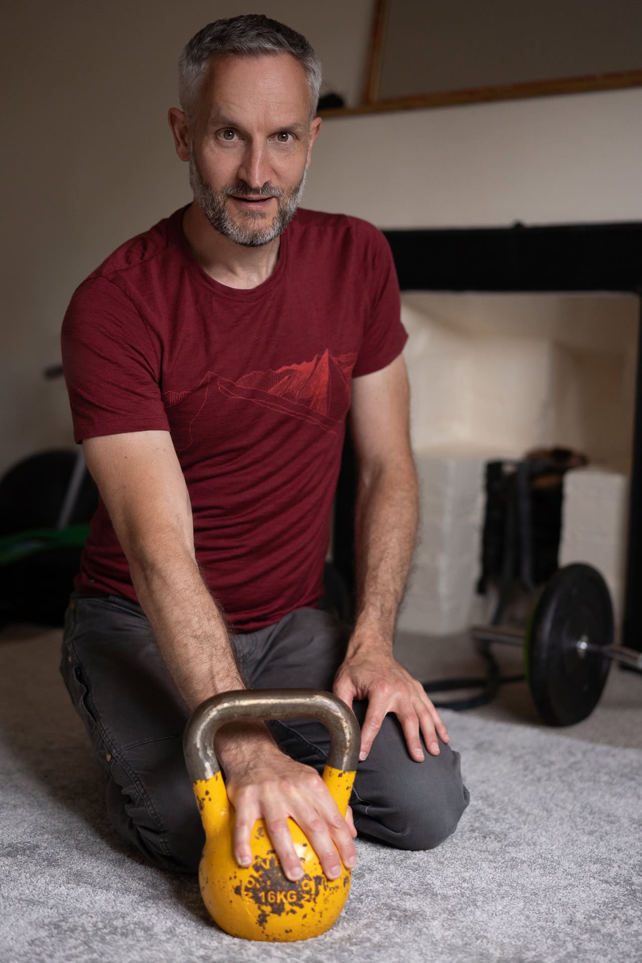 Andrew Willson kneels with a 16kg kettlebell, a London brand photographer's portrait.