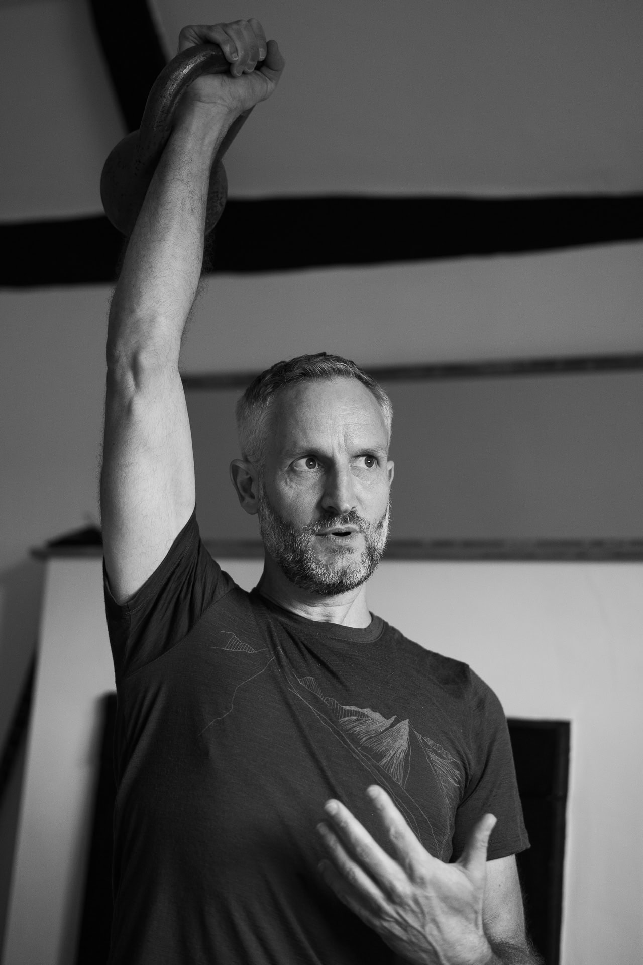 Andrew Willson, a coach, demonstrates a kettlebell press with confident focus, captured by a London brand photographer.